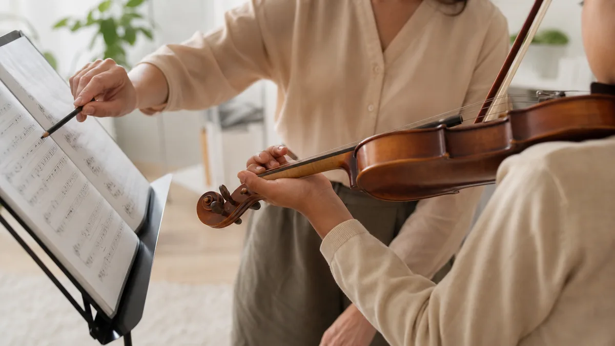Violin lesson with hands, bow, and sheet music